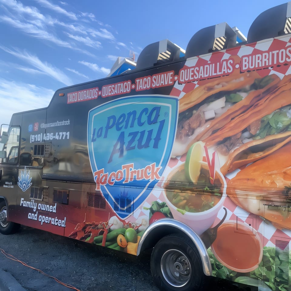 La Penca Azul Taco Truck, a black food truck with vibrant Mexican food graphics and menu items.