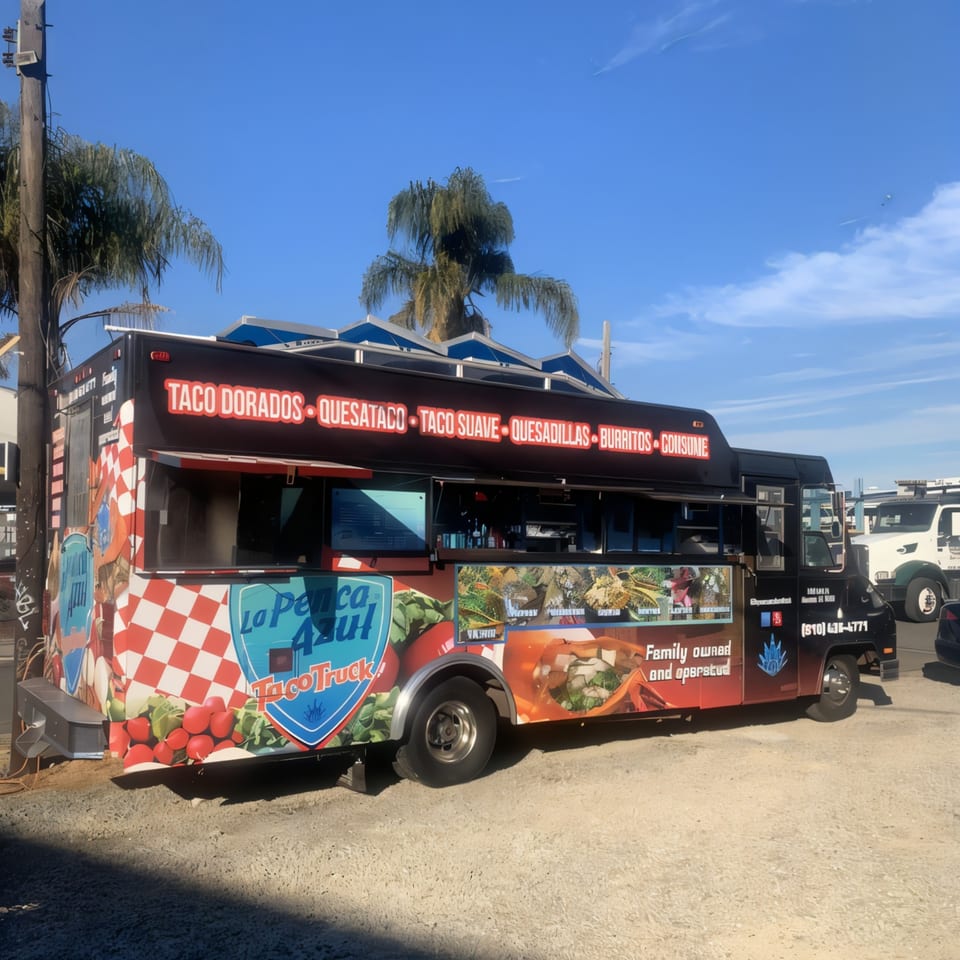 La Penca Azul Taco Truck, a black food truck with a vibrant checkered and food-themed wrap.
